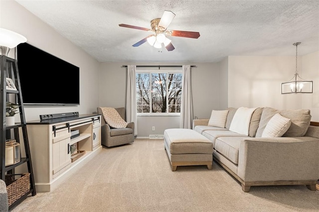 living room featuring ceiling fan with notable chandelier, light carpet, and a textured ceiling