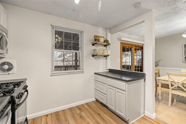 kitchen featuring white cabinetry, light hardwood / wood-style floors, gas range oven, and a healthy amount of sunlight