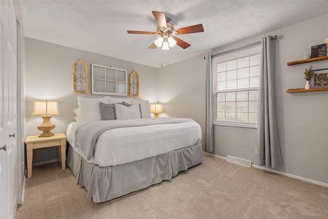 carpeted bedroom with ceiling fan and a textured ceiling