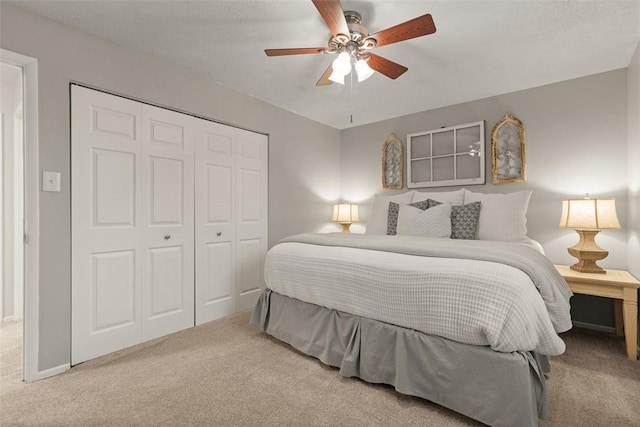 carpeted bedroom featuring ceiling fan and a closet