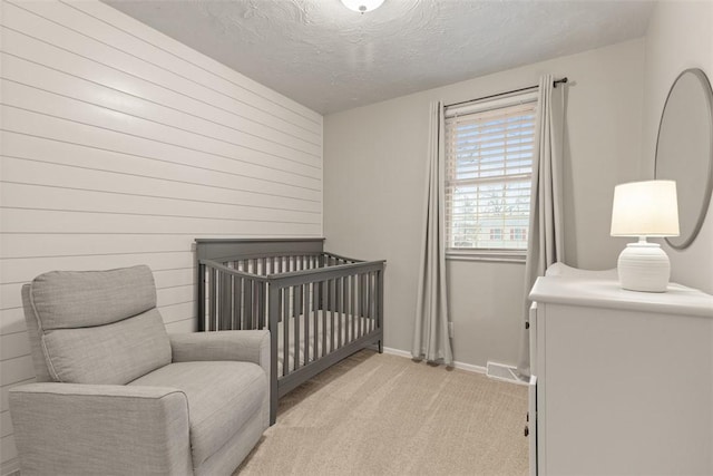 carpeted bedroom with a nursery area and a textured ceiling