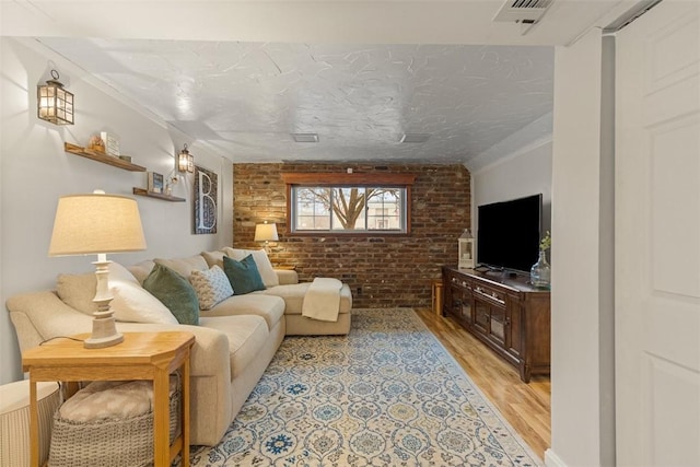 living room featuring light hardwood / wood-style flooring, a textured ceiling, and brick wall