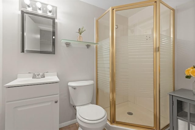 bathroom featuring vanity, a shower with shower door, and toilet