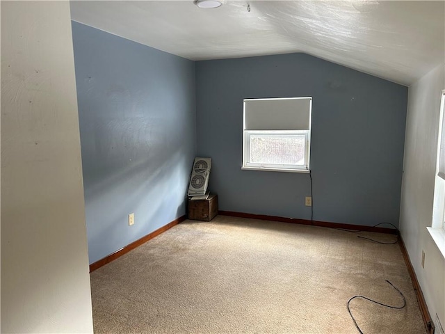 carpeted empty room featuring lofted ceiling