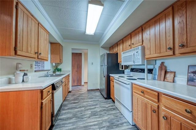 kitchen featuring ornamental molding, sink, white appliances, and light wood-type flooring