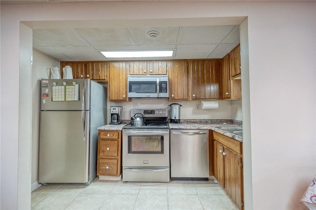 820 E Beau Unit 7Hr, South Strabane, PA 15301 - kitchen with stainless steel appliances, brown cabinets, a paneled ceiling, light tile patterned floors, and a sink