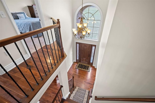 foyer featuring hardwood / wood-style flooring, a towering ceiling, and a chandelier