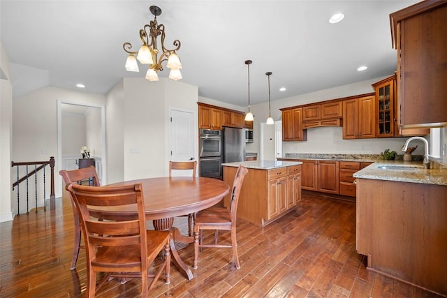 kitchen featuring sink, appliances with stainless steel finishes, hanging light fixtures, light stone countertops, and a kitchen island