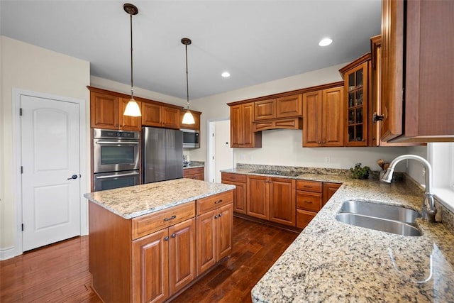 kitchen featuring a kitchen island, appliances with stainless steel finishes, sink, hanging light fixtures, and light stone countertops