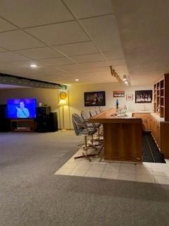 bar with a paneled ceiling and carpet flooring