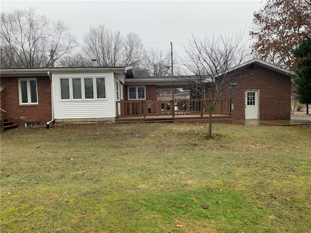 rear view of property featuring a wooden deck and a lawn