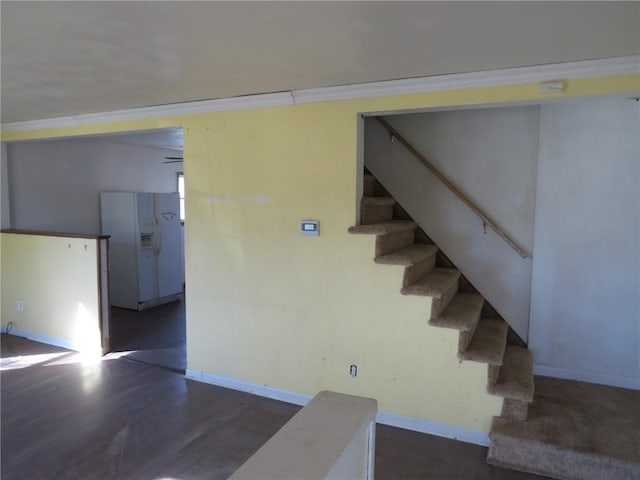 stairs with baseboards, wood finished floors, and crown molding