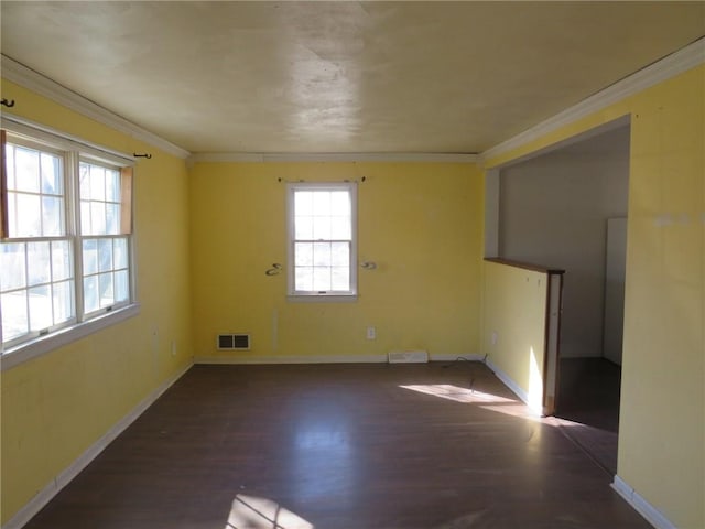 unfurnished room with visible vents, crown molding, baseboards, and wood finished floors