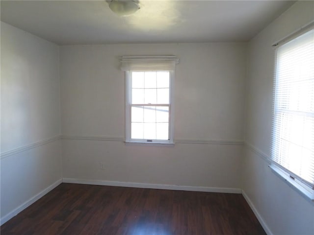 empty room featuring dark wood-style floors and baseboards