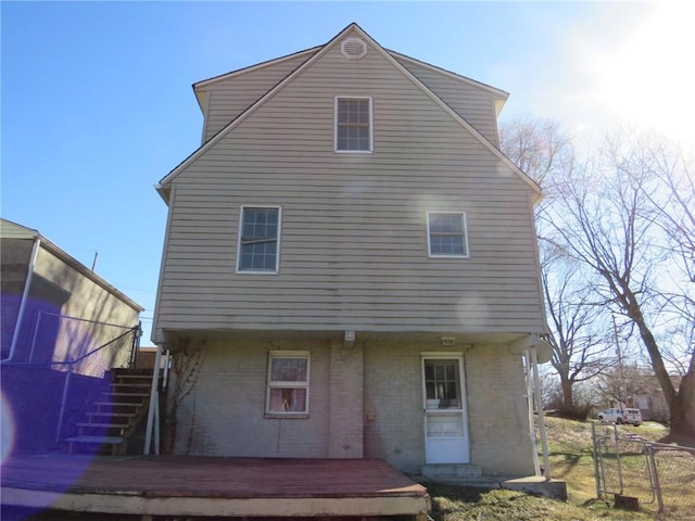 rear view of house with stairway, a deck, and fence