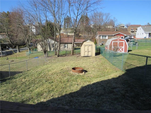 view of yard featuring a fire pit, a storage shed, an outdoor structure, and fence