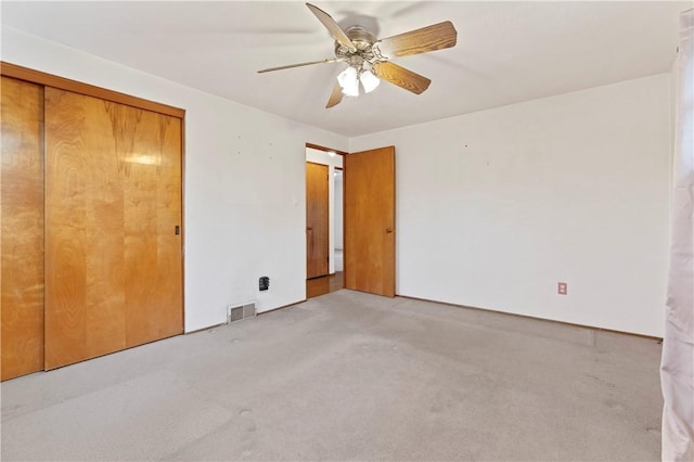 unfurnished bedroom with ceiling fan, light colored carpet, and a closet