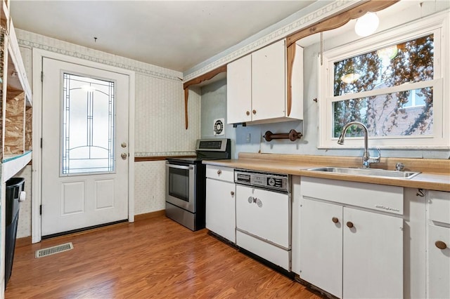 kitchen featuring sink, stainless steel range with electric stovetop, light wood-type flooring, dishwasher, and white cabinets