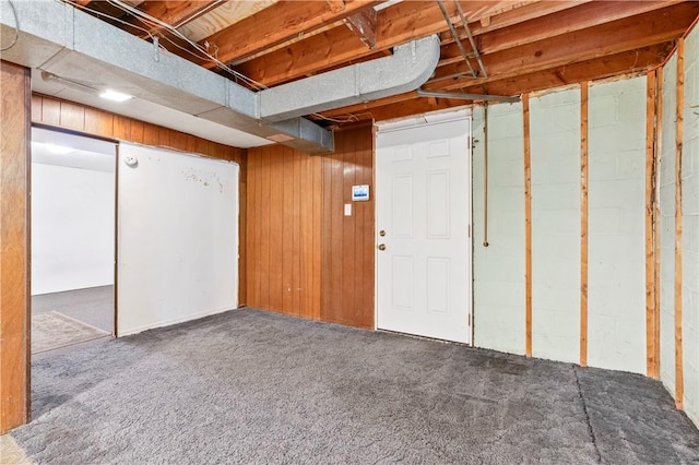 basement featuring wooden walls and dark carpet