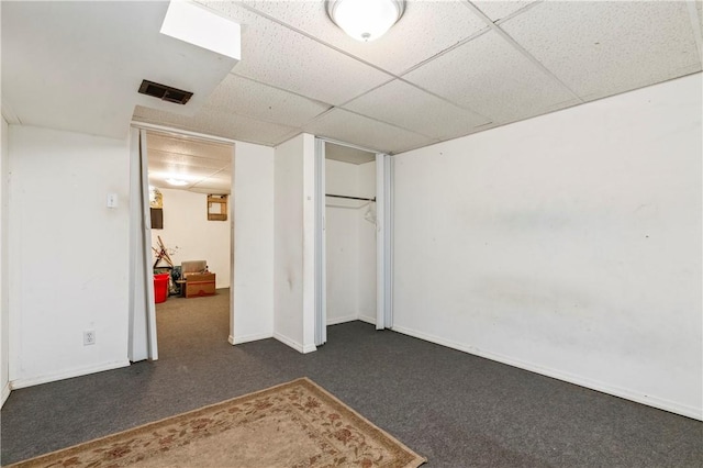 basement with dark carpet and a paneled ceiling