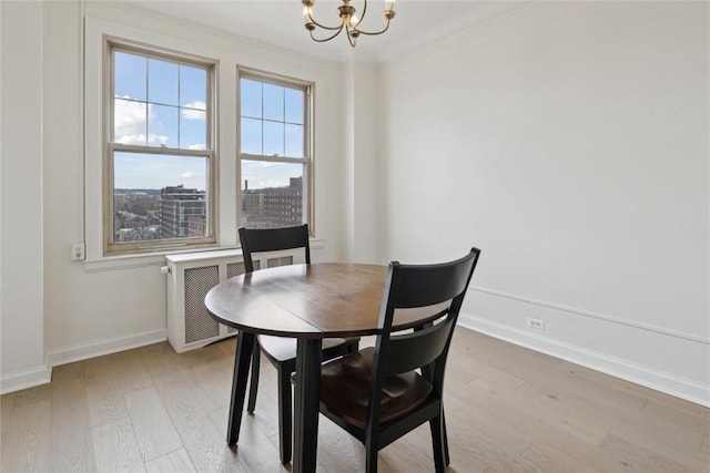 dining area with ornamental molding, a chandelier, radiator heating unit, and light wood-type flooring