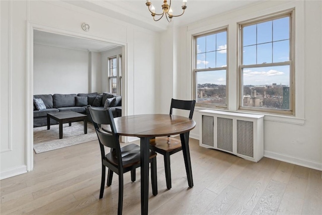 dining space with a chandelier, radiator heating unit, and light hardwood / wood-style floors