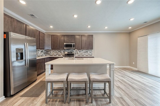 kitchen featuring tasteful backsplash, appliances with stainless steel finishes, sink, and a center island with sink