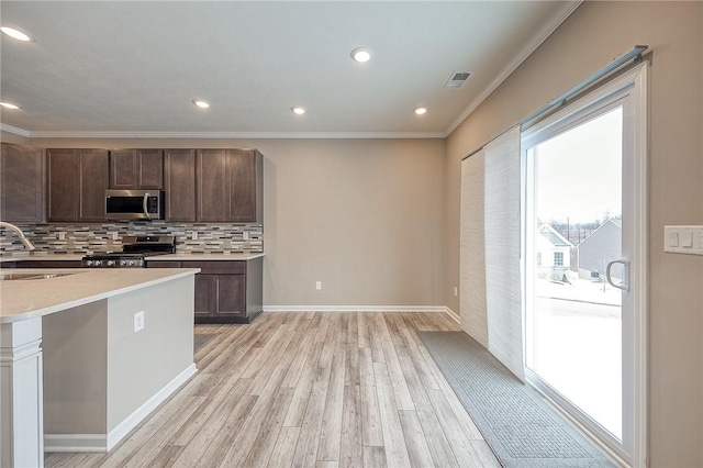 kitchen with dark brown cabinetry, sink, stainless steel appliances, light hardwood / wood-style floors, and decorative backsplash