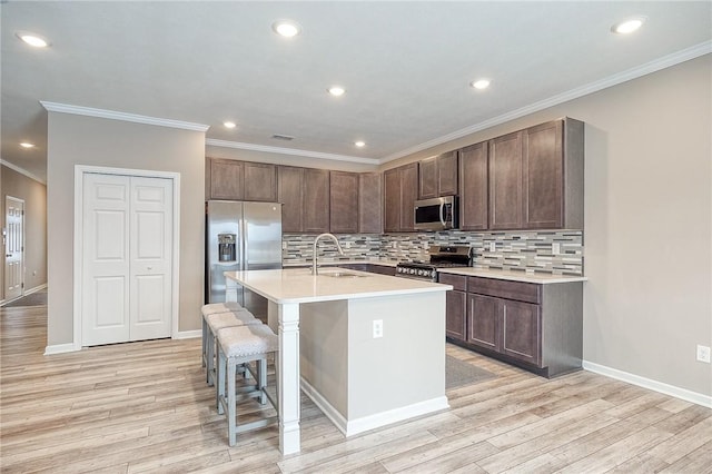 kitchen with a breakfast bar, sink, a center island with sink, light hardwood / wood-style flooring, and stainless steel appliances