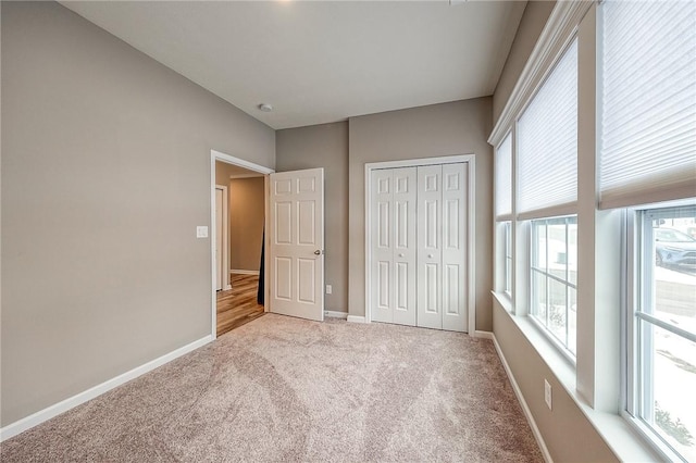 unfurnished bedroom with light colored carpet and a closet