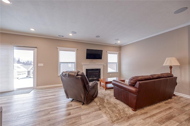 living room with crown molding, a wealth of natural light, and light hardwood / wood-style floors