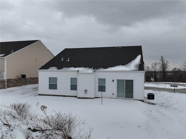 snow covered rear of property featuring central air condition unit