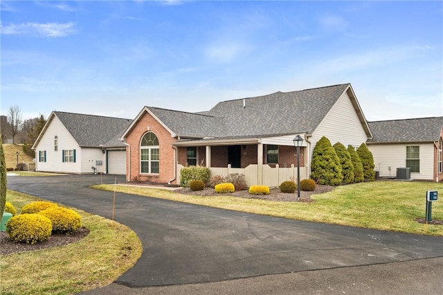 view of front of home with a garage, a front yard, and central air condition unit