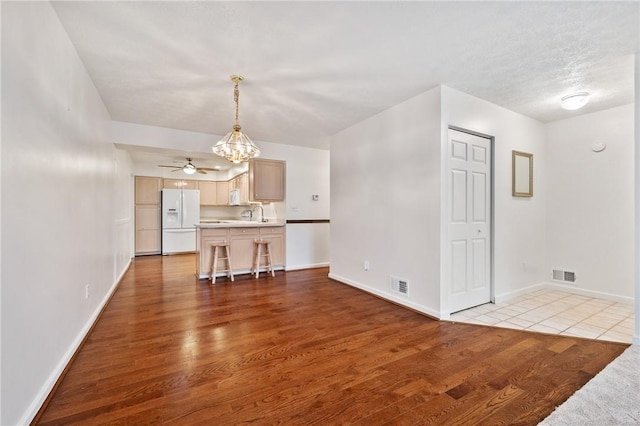 unfurnished living room featuring ceiling fan with notable chandelier and light hardwood / wood-style floors