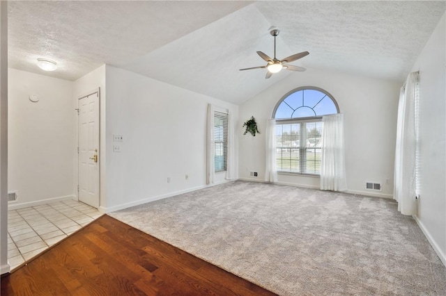 carpeted spare room with ceiling fan, lofted ceiling, and a textured ceiling