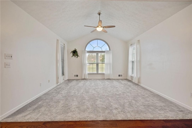 carpeted empty room featuring ceiling fan, lofted ceiling, and a textured ceiling