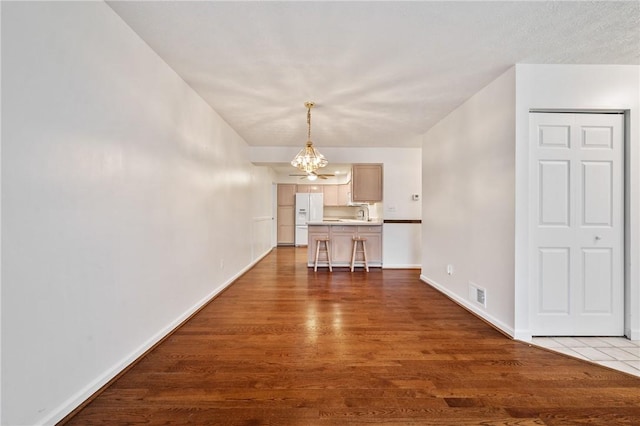 unfurnished dining area featuring dark wood-type flooring and an inviting chandelier