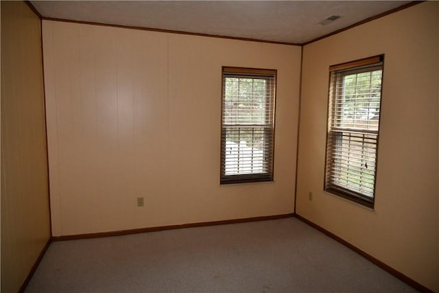 carpeted empty room with french doors, ornamental molding, and a healthy amount of sunlight