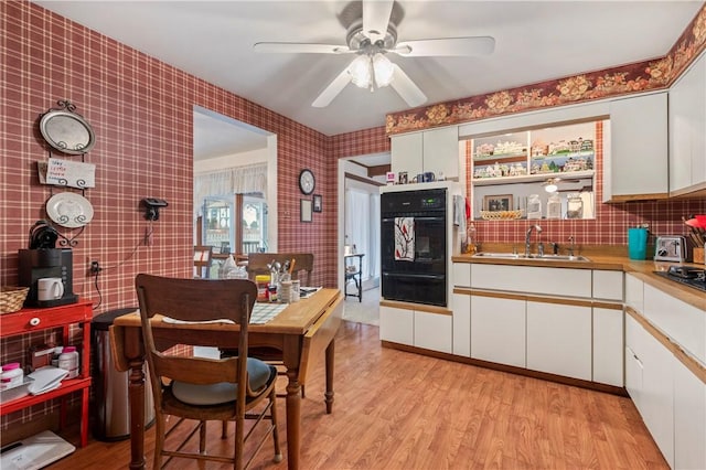 kitchen with sink, ceiling fan, light hardwood / wood-style floors, white cabinets, and oven