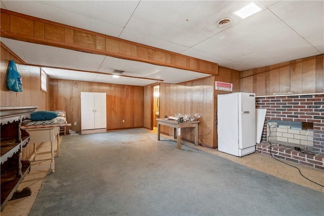 basement featuring white refrigerator and a fireplace