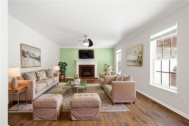 living room with hardwood / wood-style flooring, ornamental molding, a brick fireplace, and ceiling fan