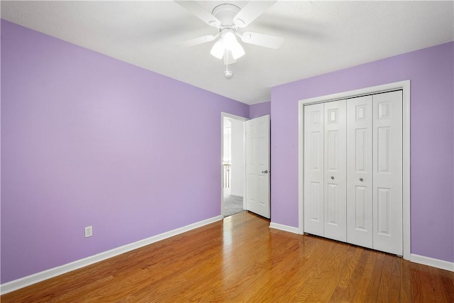 unfurnished bedroom with hardwood / wood-style flooring, ceiling fan, and a closet