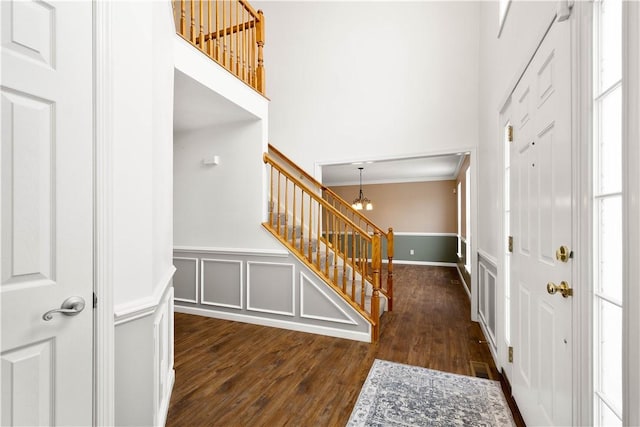 foyer featuring a high ceiling, ornamental molding, dark hardwood / wood-style floors, and an inviting chandelier