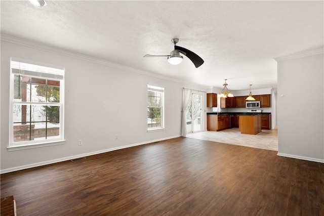 unfurnished living room with wood-type flooring, a textured ceiling, ceiling fan, and crown molding