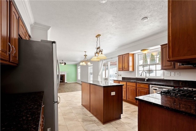 kitchen featuring sink, crown molding, a center island, pendant lighting, and dark stone counters