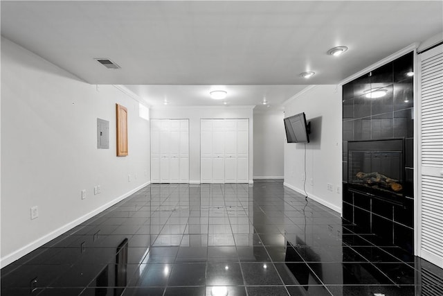 empty room featuring crown molding, electric panel, and a fireplace