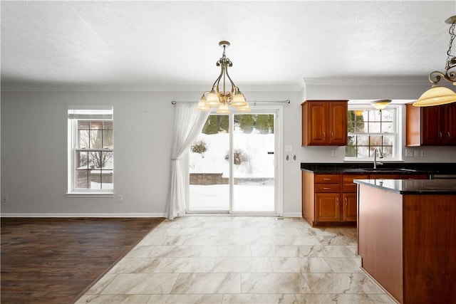 kitchen with a wealth of natural light, ornamental molding, pendant lighting, and a textured ceiling