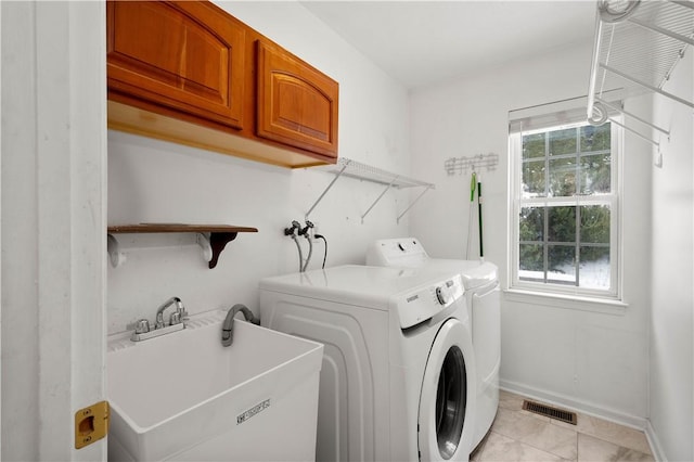 clothes washing area featuring cabinets, sink, light tile patterned floors, and washer and clothes dryer