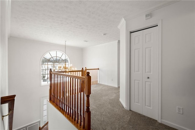 hall featuring crown molding, a chandelier, carpet floors, and a textured ceiling