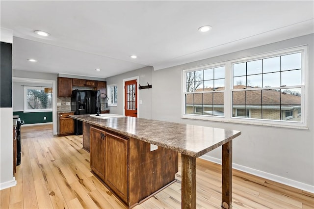 kitchen with sink, plenty of natural light, light hardwood / wood-style floors, and a center island with sink